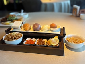 A tray with various food items including noodles, dumplings, and a bread roll. - Jingshan Garden Hotel (Beijing)