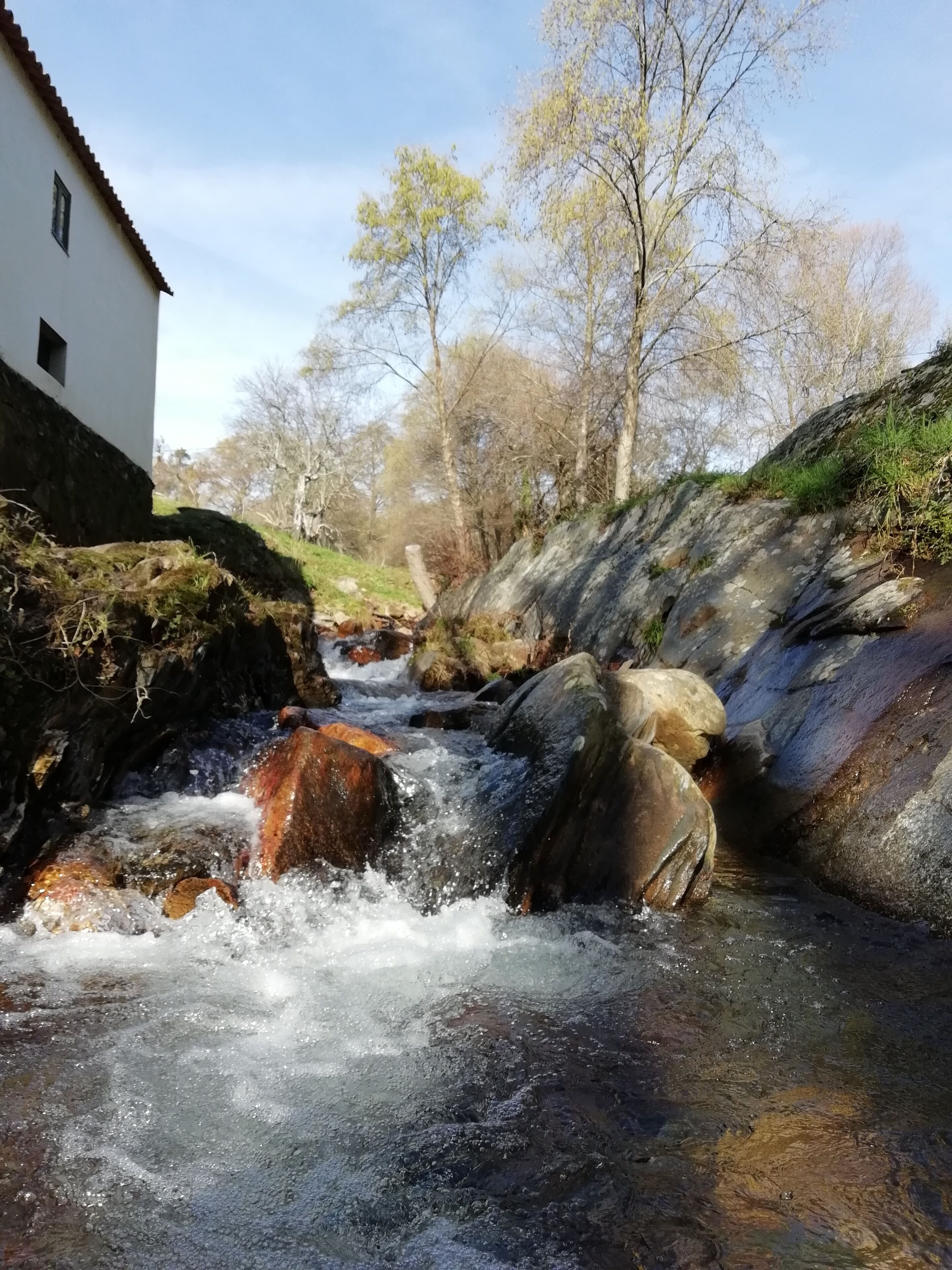 A river flowing through a rocky landscape with a building on the left.