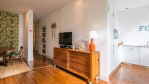 Un salon moderne avec un meuble de rangement en bois, un téléviseur et une lampe.