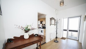A spacious room with a wooden table, a potted plant, and a view of the kitchen and balcony. - The Snug-2Bed Apt sleeps 4 with fab sea views directly on the Wild Atlantic Way (Dunkineely)