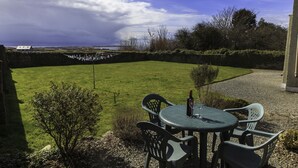 A patio with a table and chairs, a bottle of wine, and a view of the sea. - The Snug-2Bed Apt sleeps 4 with fab sea views directly on the Wild Atlantic Way (Dunkineely)