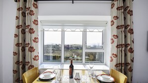 A dining table set for two with a view of a rural landscape through a window. - The Snug-2Bed Apt sleeps 4 with fab sea views directly on the Wild Atlantic Way (Dunkineely)