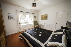 Une chambre à coucher avec un grand lit, une chaise, un radiateur et une porte.