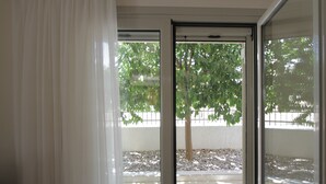 A view through a glass door with a tree and a white wall in the background.