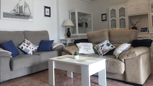 A living room with a beige sofa set, a white coffee table, and a cabinet with glass doors.