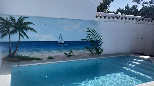 A swimming pool with a mural of a beach scene, including palm trees and a sailboat.