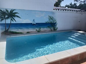 A swimming pool with a mural of a beach scene, including palm trees and a sailboat. - Cozy house with pool near Cordoba (Encinarejo de Córdoba)