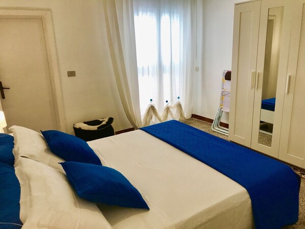Una habitación de hotel con cama, armario y ventana con cortinas.
