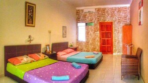 Quarto de hotel com duas camas, uma parede de pedra, uma porta vermelha e uma cadeira de vime.