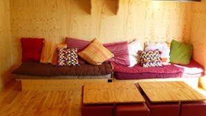 Ein Holzinnenraum mit einer Couch, Kissen und einem Holztisch.