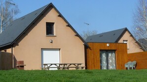 Ein zweistöckiges Gebäude mit Satteldach, Garage und einem Picknicktisch davor.