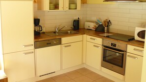 Eine kleine Küche mit weißen Schränken, einer Edelstahl-Spüle, einem Backofen und einer Mikrowelle.