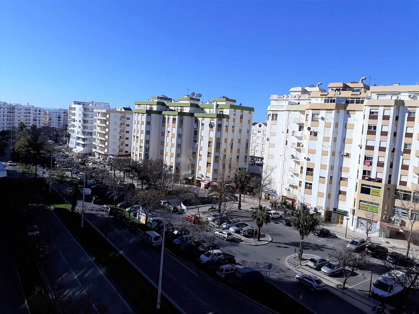 A multi-story residential building with a central courtyard, surrounded by other buildings.