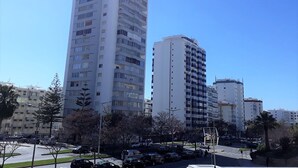 A high-rise residential building with multiple balconies, surrounded by other buildings and a parking area. - Torre 6- Family, Wi-fi, Central and 80mt Beach (Quarteira)