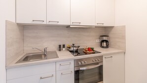 A modern kitchen with white cabinets, a stainless steel sink, a stove, and a coffee maker. - Ansbachs City Apartment (Ansbach)