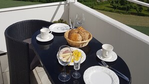 A balcony with a table set for a meal, overlooking a town with red-roofed buildings and greenery. - Ansbachs City Apartment (Ansbach)