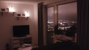 A living room with a large window, a flat-screen TV, and a sofa. - Ansbachs City Apartment (Ansbach)