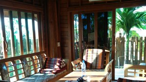 A wooden cabin interior with a sofa, dining table, and chairs.