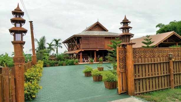 A traditional wooden building with a sloped roof, surrounded by a wooden fence and lush greenery.