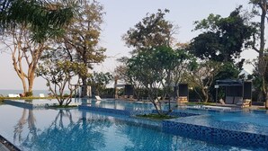 A pool with clear blue water, surrounded by lounge chairs and shaded areas. - Baan San Dao Hua Hin (Hua Hin)