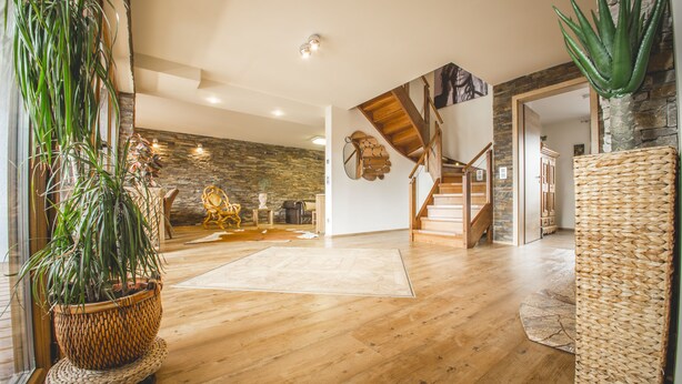 A spacious living area with a wooden floor, a large woven plant pot, and a staircase leading to an upper level.