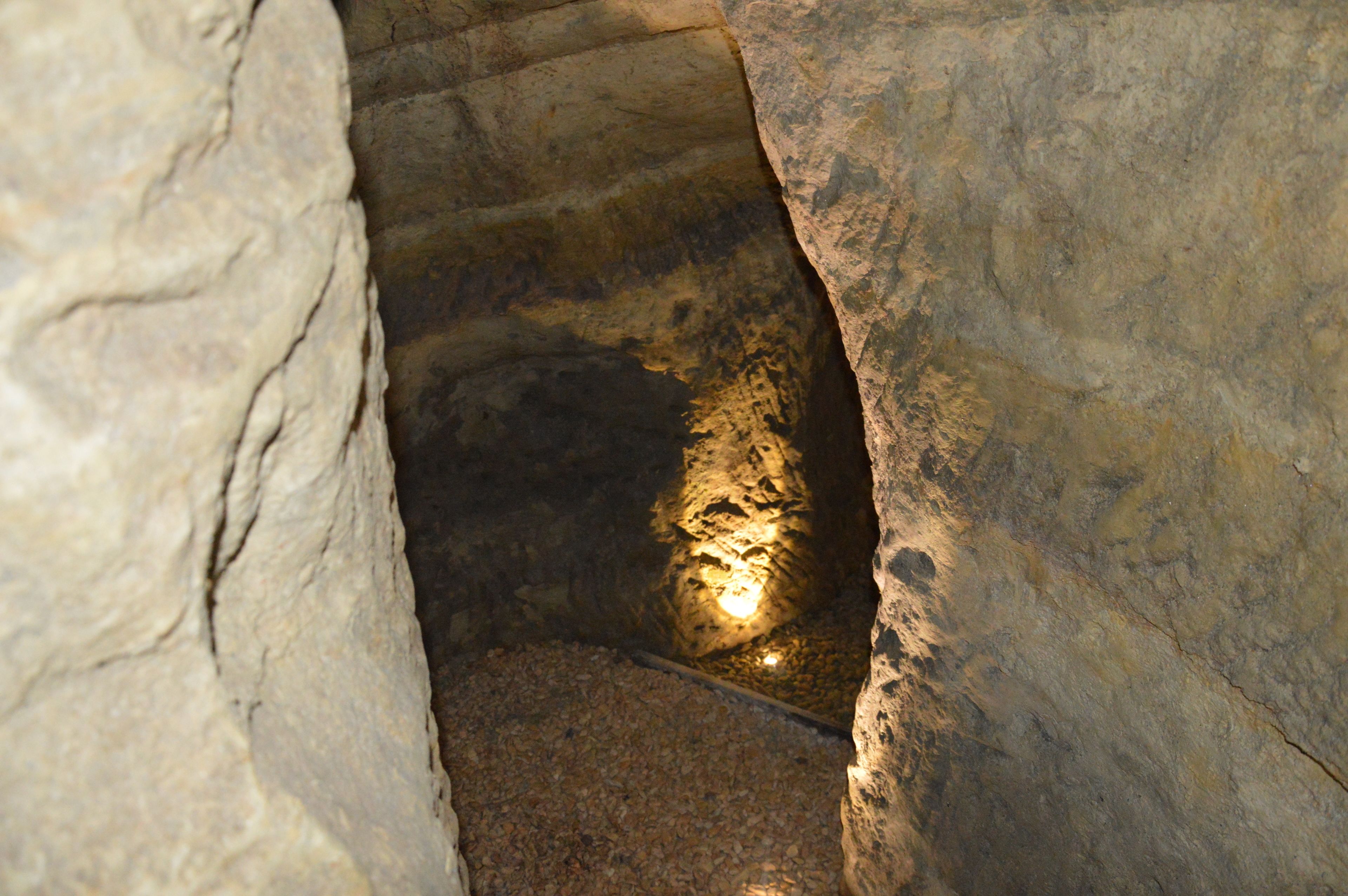 Un escalier étroit en pierre, avec une source de lumière en bas.