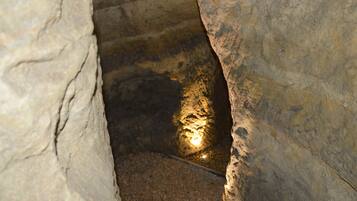 Un escalier étroit en pierre, avec une source de lumière en bas.