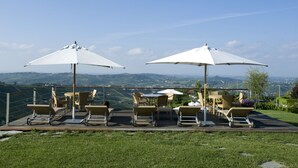 Een terras met buitenstoelen en parasols, met uitzicht op een prachtig landschap.