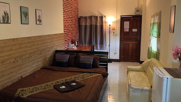 A hotel room with a bed, a sofa, a small table, and a refrigerator. - Sandee Place Chomthong (Chom Thong)