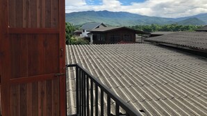 A traditional wooden door leading to a balcony with a tiled roof overlooking a mountainous landscape. - Sandee Place Chomthong (Chom Thong)