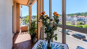 A balcony with a potted plant, a vase with flowers, and a clear view of the street and buildings. - Convenient Arcachon T2 Apt - Balcony, Elevator, Secure Garage Near Shops & Train Station (Arcachon)