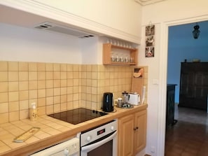 A compact kitchen with a stove, oven, and a coffee maker on the countertop. - Homerez - Apartment in Arles (Arles)