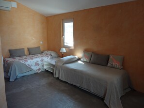 A bedroom with two beds, a window, and a lamp.