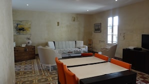 Un salon comprenant un canapé, une table basse, une table à manger avec des chaises, un meuble pour la télévision et un sol à motifs.