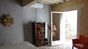 Une pièce avec un lit, une armoire, une chaise rouge et un sol à motifs.
