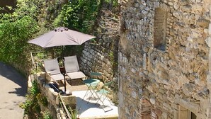 Edificio de piedra con un patio que tiene mobiliario exterior y un gran paraguas.
