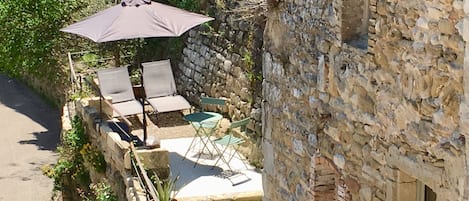 A stone building with a patio area featuring outdoor seating and a large umbrella.