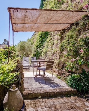 An outdoor patio with a table and chairs, a pergola, and a stone wall.