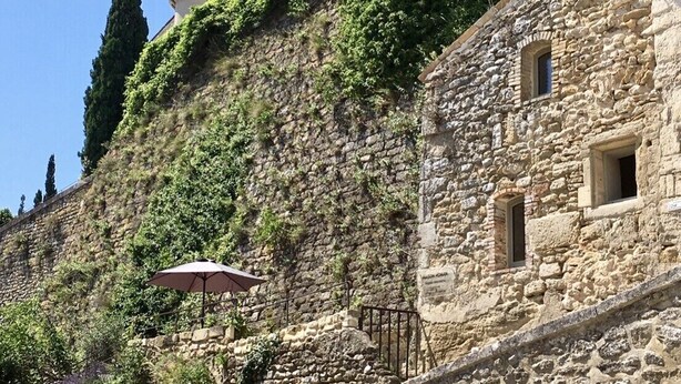 Un edificio de piedra con muros cubiertos de hiedra y una pequeña torre.