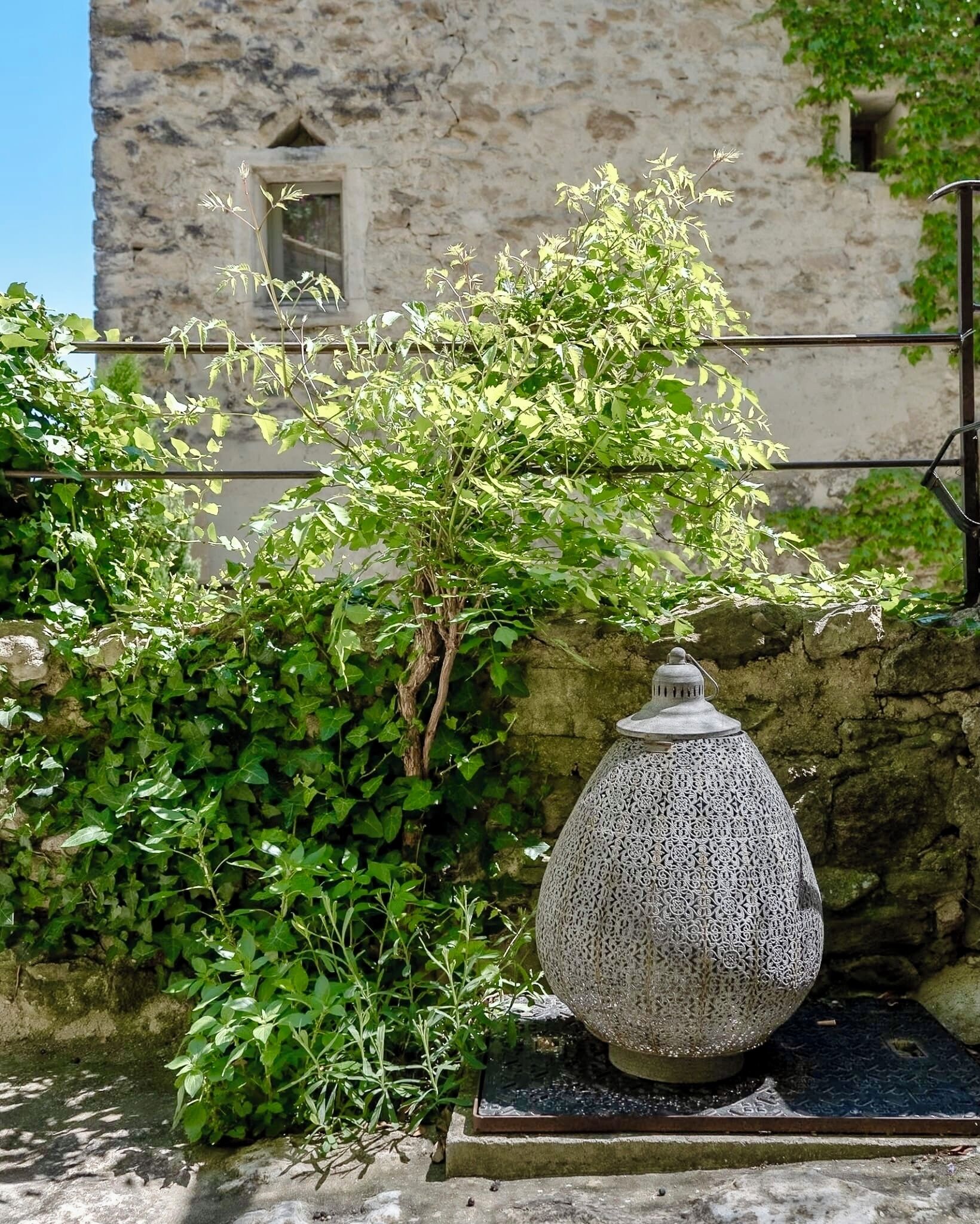 A stone wall with a decorative ceramic pot and lush green foliage.