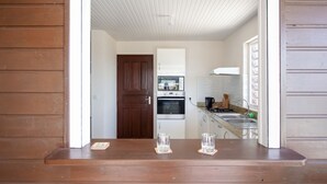 A kitchen with a wooden countertop, two glasses, and a door leading to another room. - Villa F3 standing and all comfort in Petit-Bourg in Guadeloupe (PETIT-BOURG)