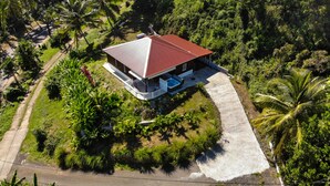An aerial view of a house with a red roof, surrounded by lush greenery and a concrete pathway leading to the entrance. - Villa F3 standing and all comfort in Petit-Bourg in Guadeloupe (PETIT-BOURG)