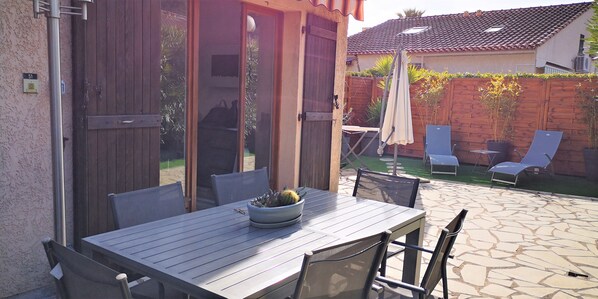 A patio area with a table and chairs, a potted plant, and a wooden fence.