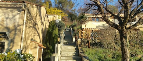 A stone staircase leading up to a building with a tiled roof, surrounded by greenery and trees.