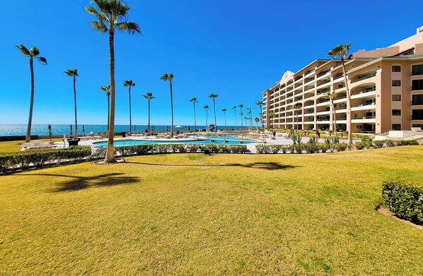 A resort with a swimming pool, palm trees, and a view of the ocean.