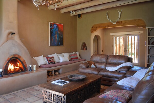 A cozy living room with a fireplace, leather sofas, a coffee table, and a painting on the wall.