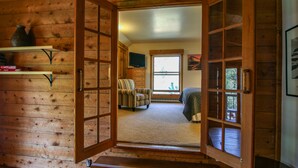 A wooden cabin interior with a bed, a chair, and a television on a shelf. - Private Cabin in beautiful Downtown Steamboat! BEST LOCATION in OLD TOWN! (Steamboat Springs)