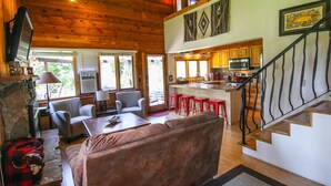 A spacious living area with a brown sofa, a television, and a fireplace. There is a kitchen area with a microwave and a dining table. - Private Cabin in beautiful Downtown Steamboat! BEST LOCATION in OLD TOWN! (Steamboat Springs)