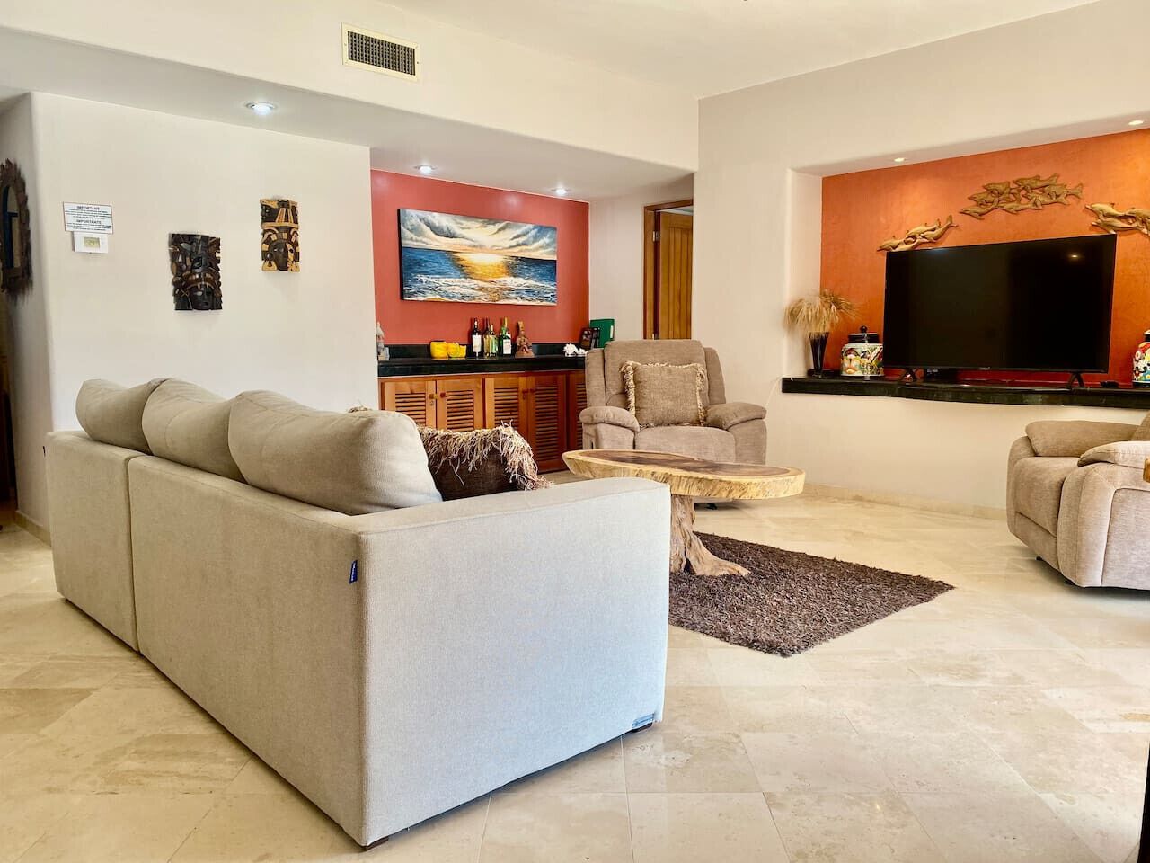 A modern living room with a sofa, armchairs, a coffee table, and a flat-screen TV.