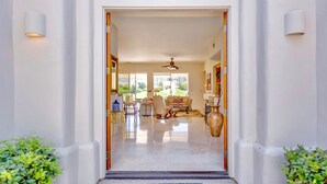 A modern entrance with a clear view into a well-lit living area featuring a sofa, chairs, and a coffee table. - Breathtaking views from your private pool & spa in PGA West: 3 BD/STR #065869 (La Quinta)